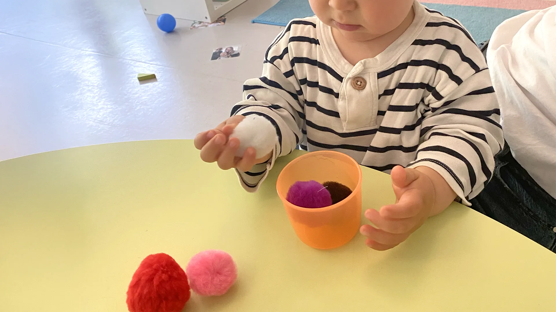 Enfants de la crèche La Nanosphère manipulant des pompons colorés dans des boîtes, concentrés sur une activité de transvasement à Lausanne.
