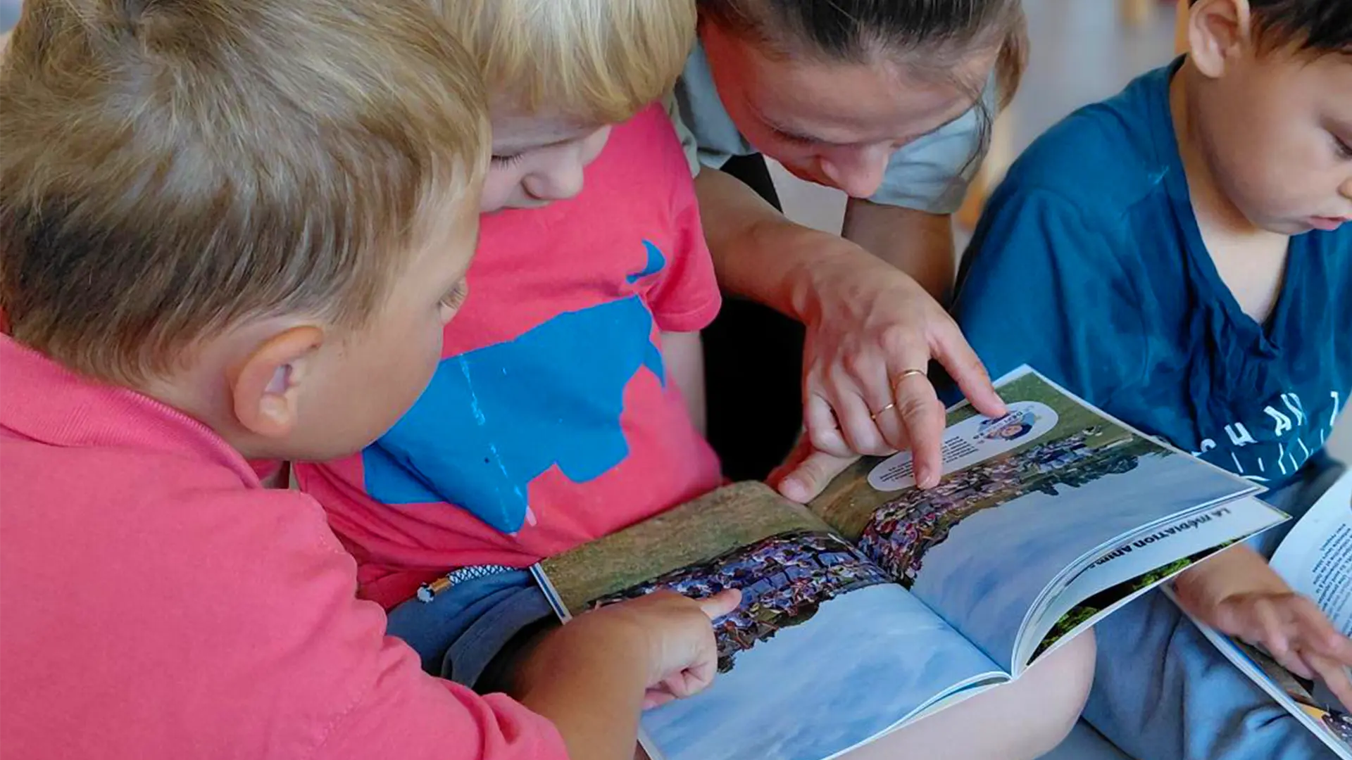 Enfants de la crèche La Nanosphère feuilletant le Yodli avec les éducateurs, revivant les souvenirs de l’année à Lausanne (EPFL).